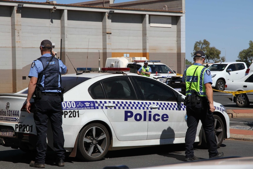 Police stand next to a police car outside a South Hedland mall where a man was shot dead.