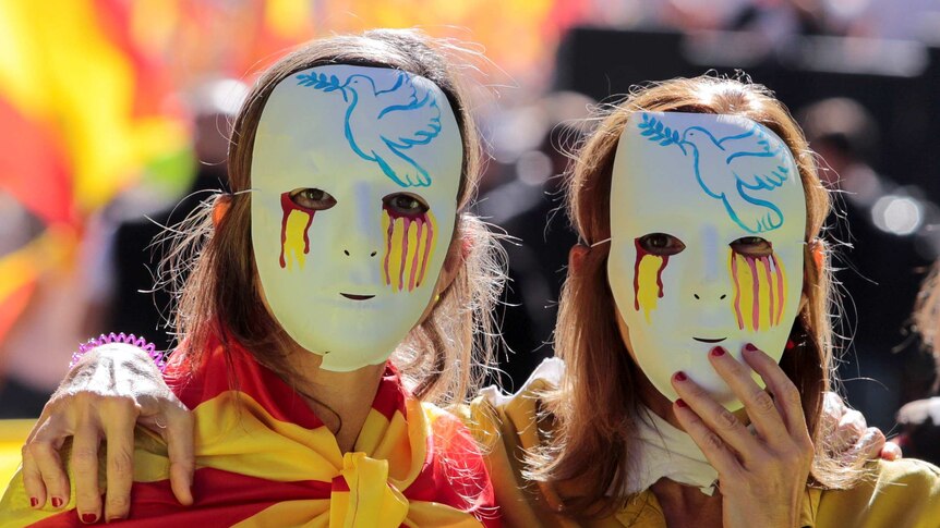 Two women wear masks with a peace dove and tears in Spanish national colours.