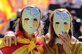 Two women wear masks with a peace dove and tears in Spanish national colours.