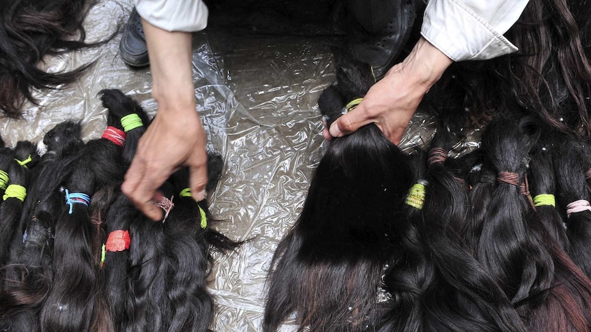 A vendor displays human hair at a wholesale market