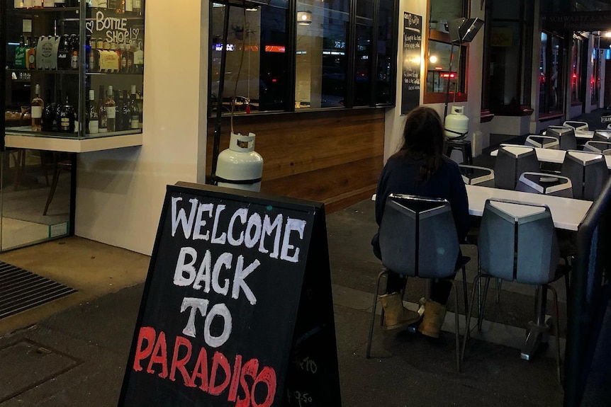 A chalkboard sign outside a restaurant saying "welcome back to Paradiso".