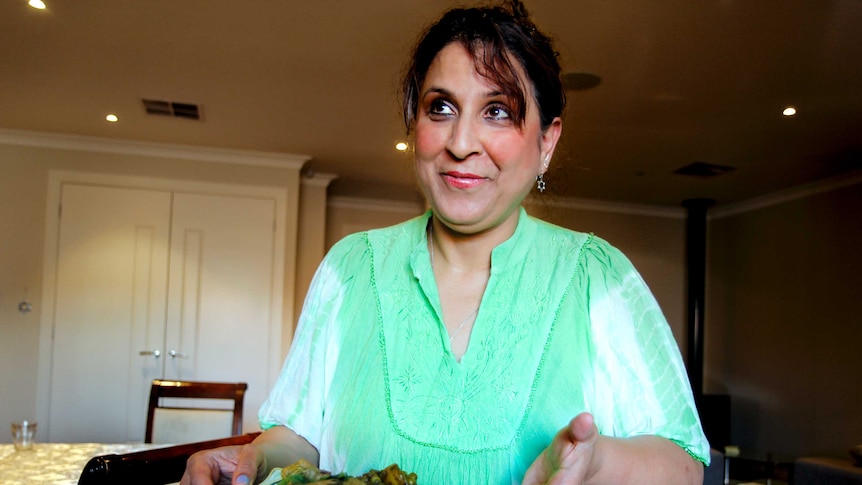 Woman holds dish of curry and rice.