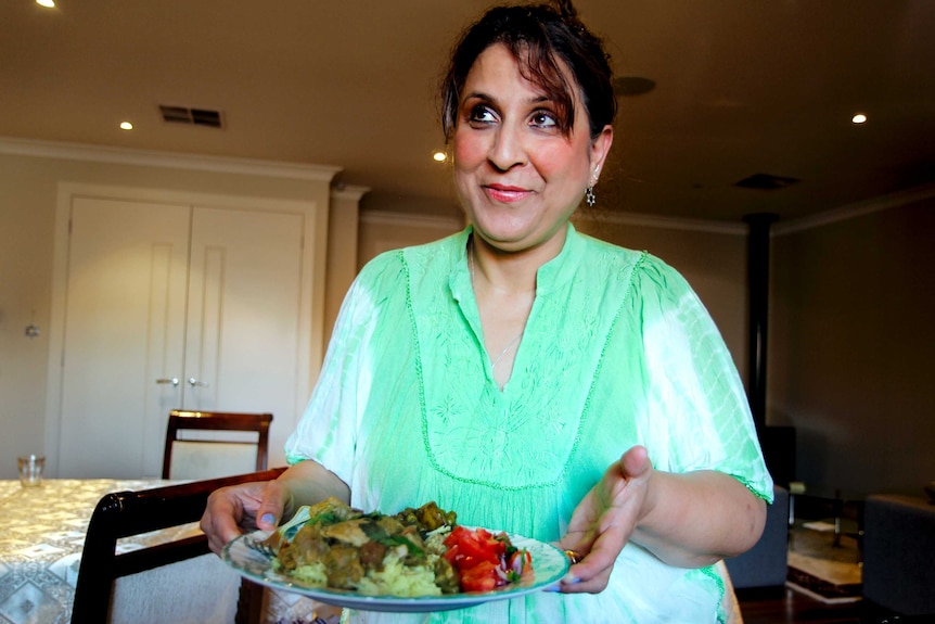 Woman holds dish of curry and rice.