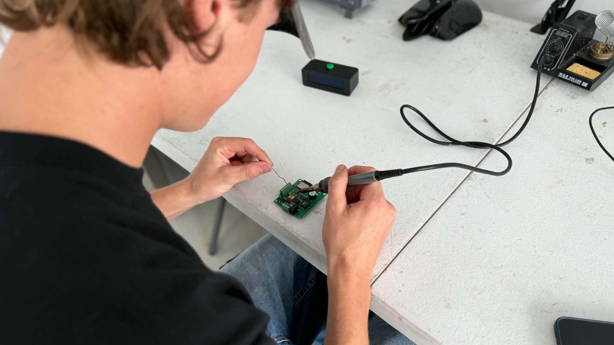 Man with hands working on electrical board