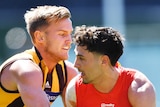 A Hawthorn AFL player contests for the ball with a Gold Coast opponent.