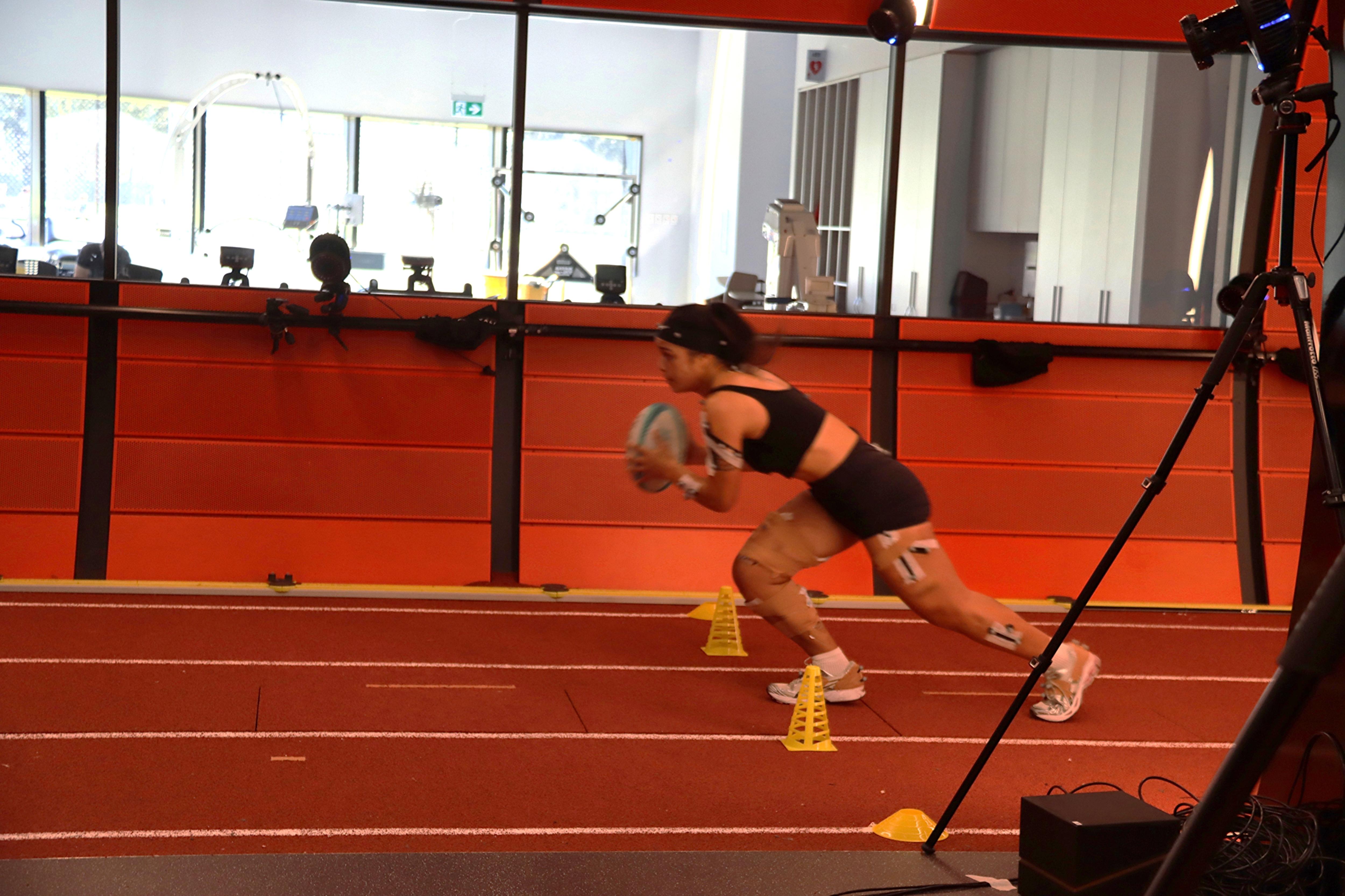 Un jugador de rugby acelera y sostiene una pelota de rugby.