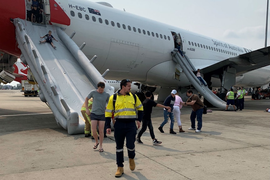 A small oy coming down a slide out of an aircraft