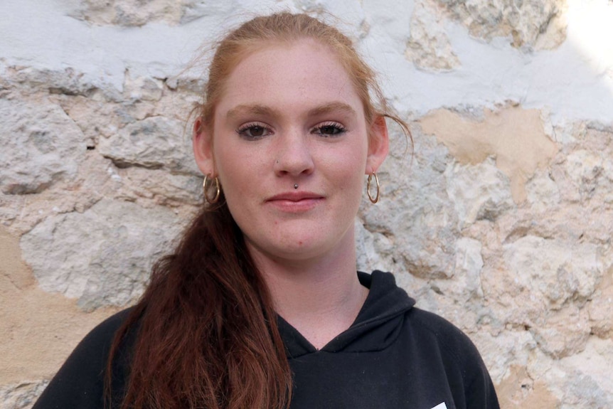 Head and shoulder shot of Lily Williams standing against a limestone wall.