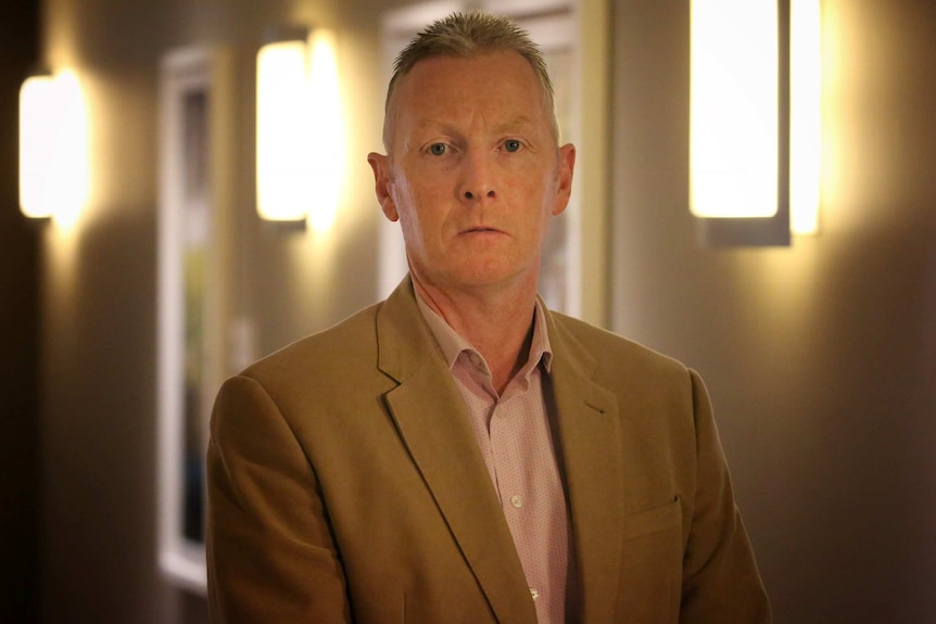 A photo of a sombre man wearing a suit.