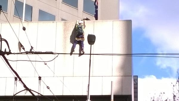 Protester is left dangling after falling while abseiling in the Melbourne CBD