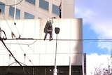 Protester is left dangling after falling while abseiling in the Melbourne CBD