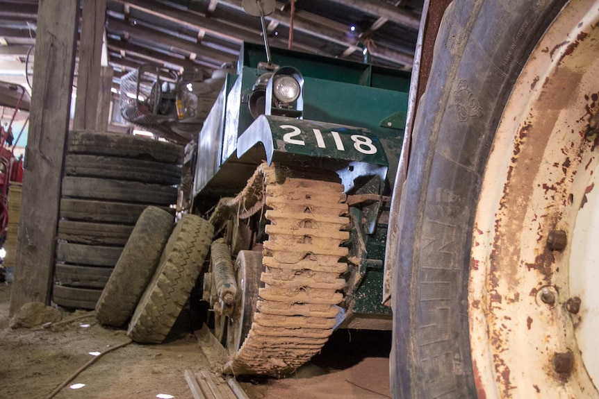 A military vehicle like a tank or jeep in a farm shed