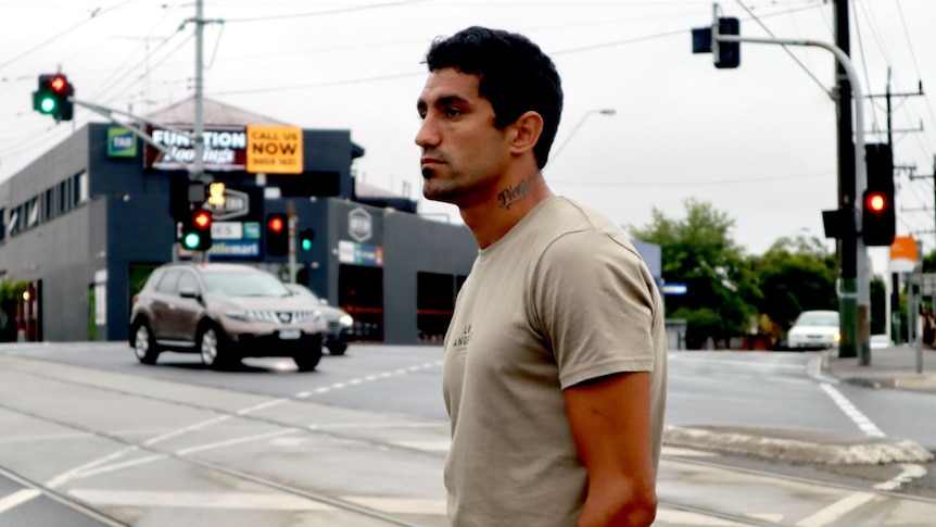 A man stands at the lights of a busy street crossing