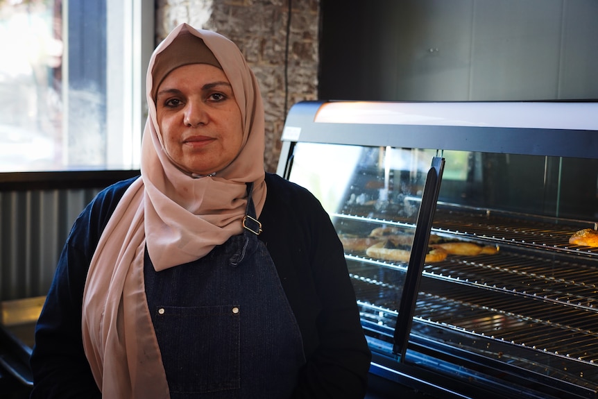 a woman in a hijab stands beside a plate of pastries
