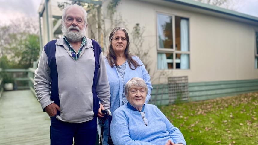 Three people in front of granny flat, one in wheelchair