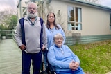 Three people in front of granny flat, one in wheelchair