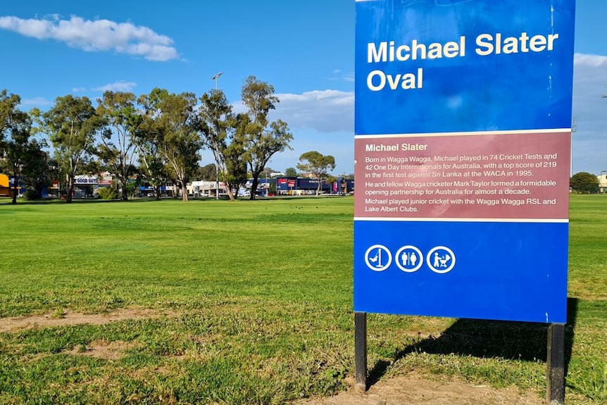 A sign that says "Michael Slater Oval" in front of a sports ground.