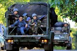 Filipino government soldiers with machine guns and green and blue army fatigues ride in the back of a vehicle near Marawi city.