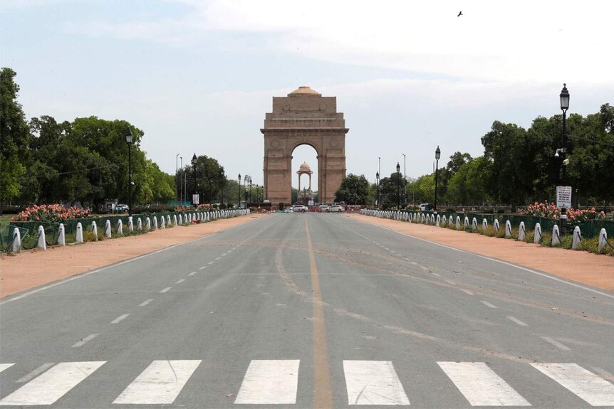 India Gate is visible from the an empty road in front. The sky is clear