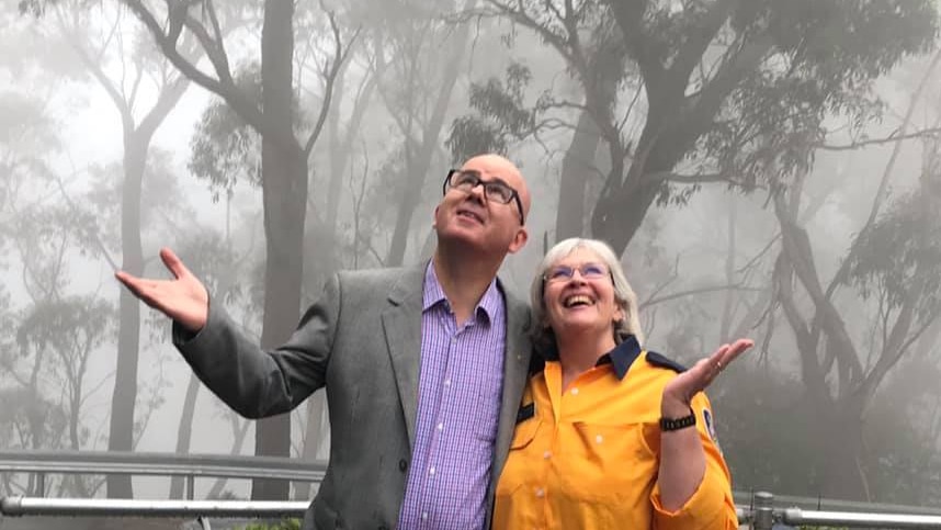 man and woman looking up and smiling under rain