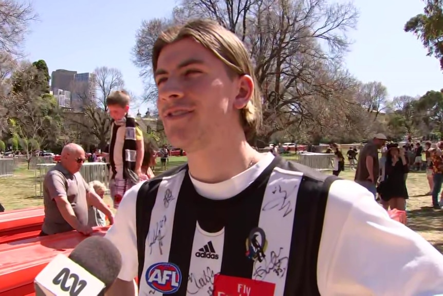 A young man wearing a Collingwood jersey over a white T-shirt.