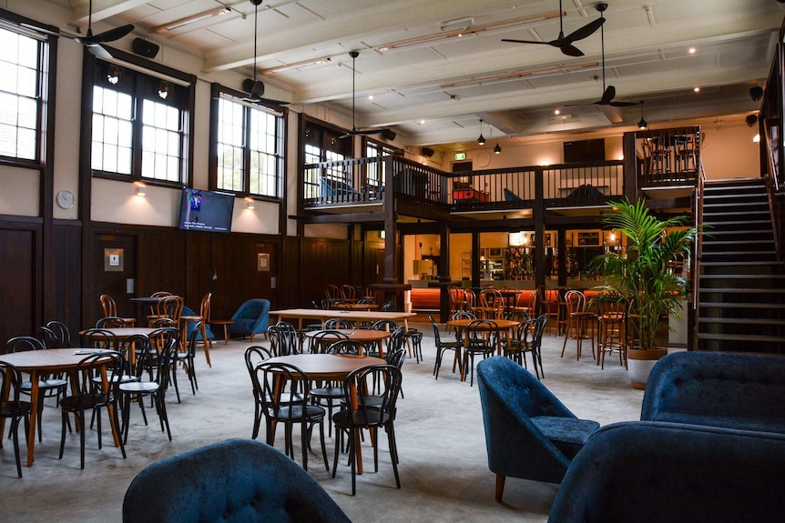 A wide shot of the empty interior of the The Tavern at the University of Western Australia, with chairs and tables and a bar.