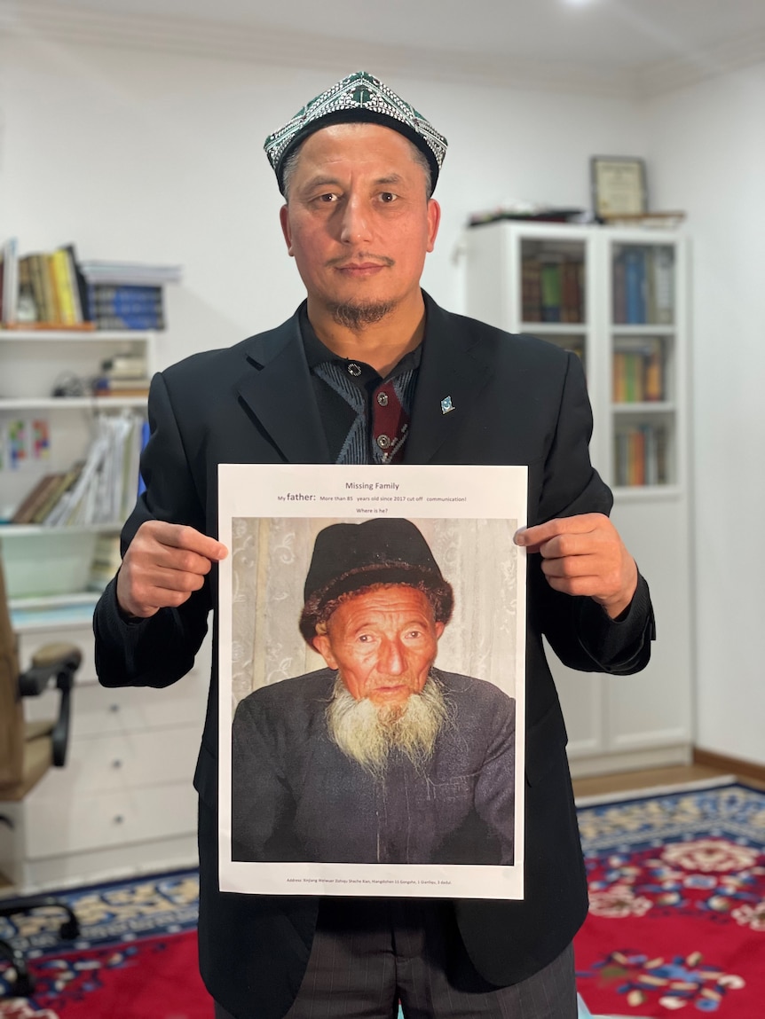 A man wearing a hat holding a poster of an older man wearing a hat