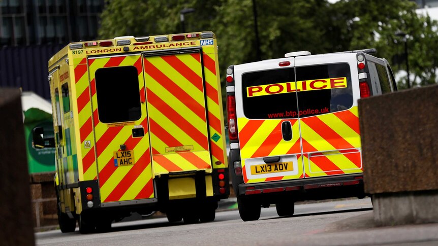 An ambulance waits next to a police car.