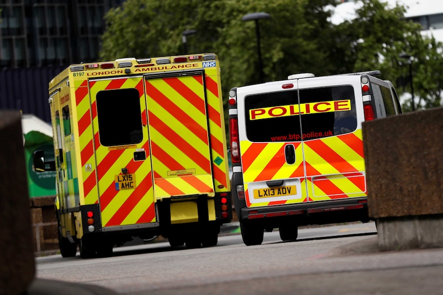 An ambulance waits next to a police car.