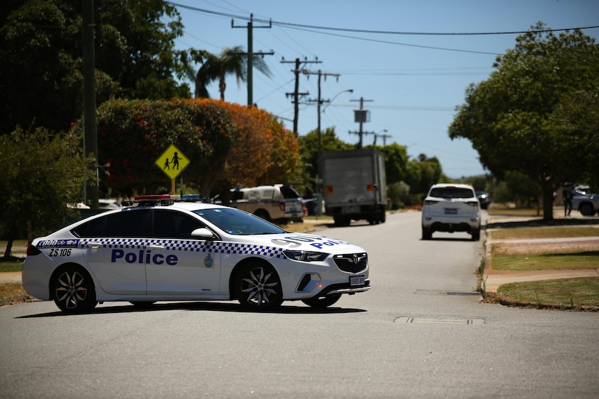 A police car blocks a street in a suburban neighbourhood