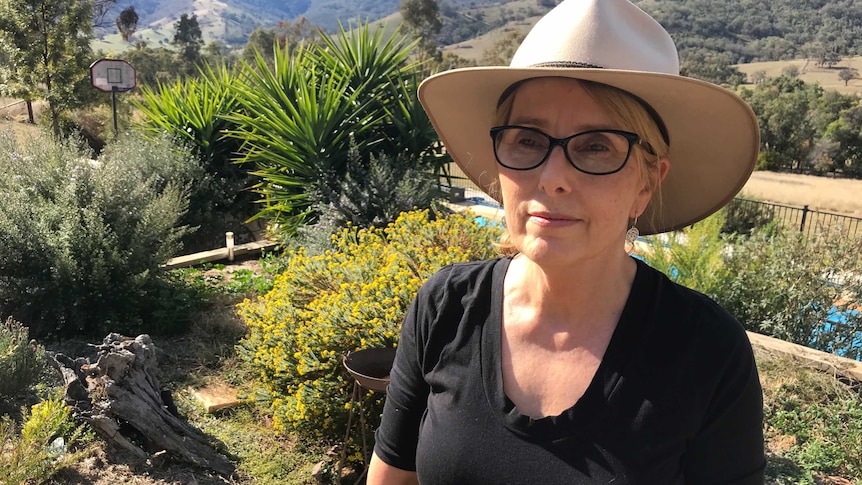 A woman in a hat with a native garden in the background