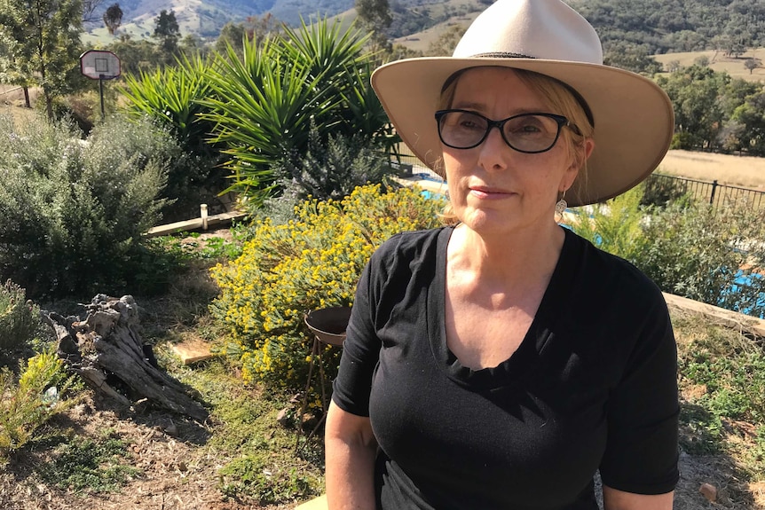 A woman in a hat with a native garden in the background