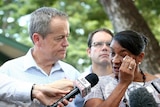 Nova Peris wipes a tear from her eye as she stands in front of microphones