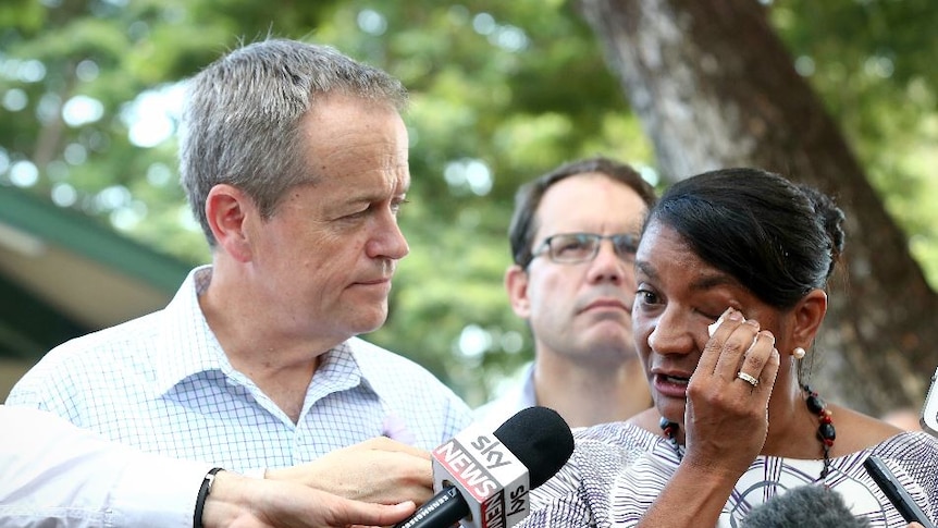 Nova Peris wipes a tear from her eye as she stands in front of microphones