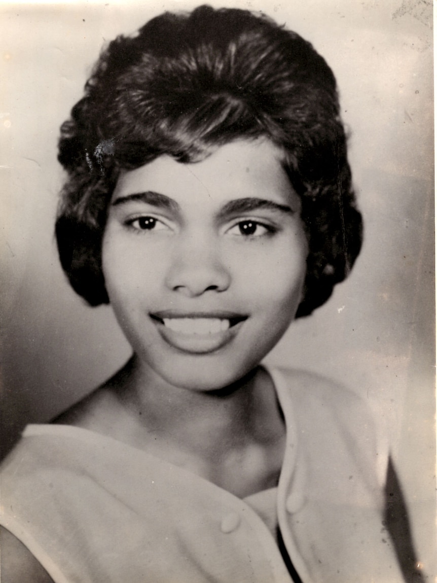 A black and white photo shows a smiling woman.
