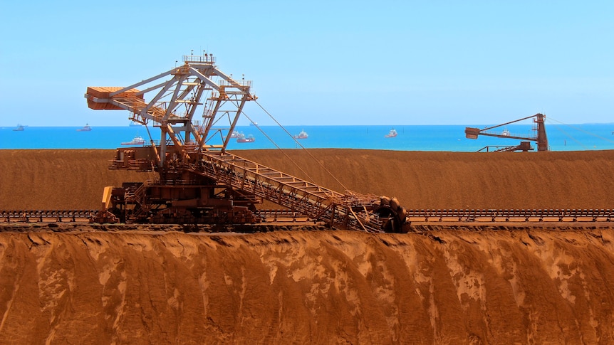 Iron ore stockpiles line up on a coastline