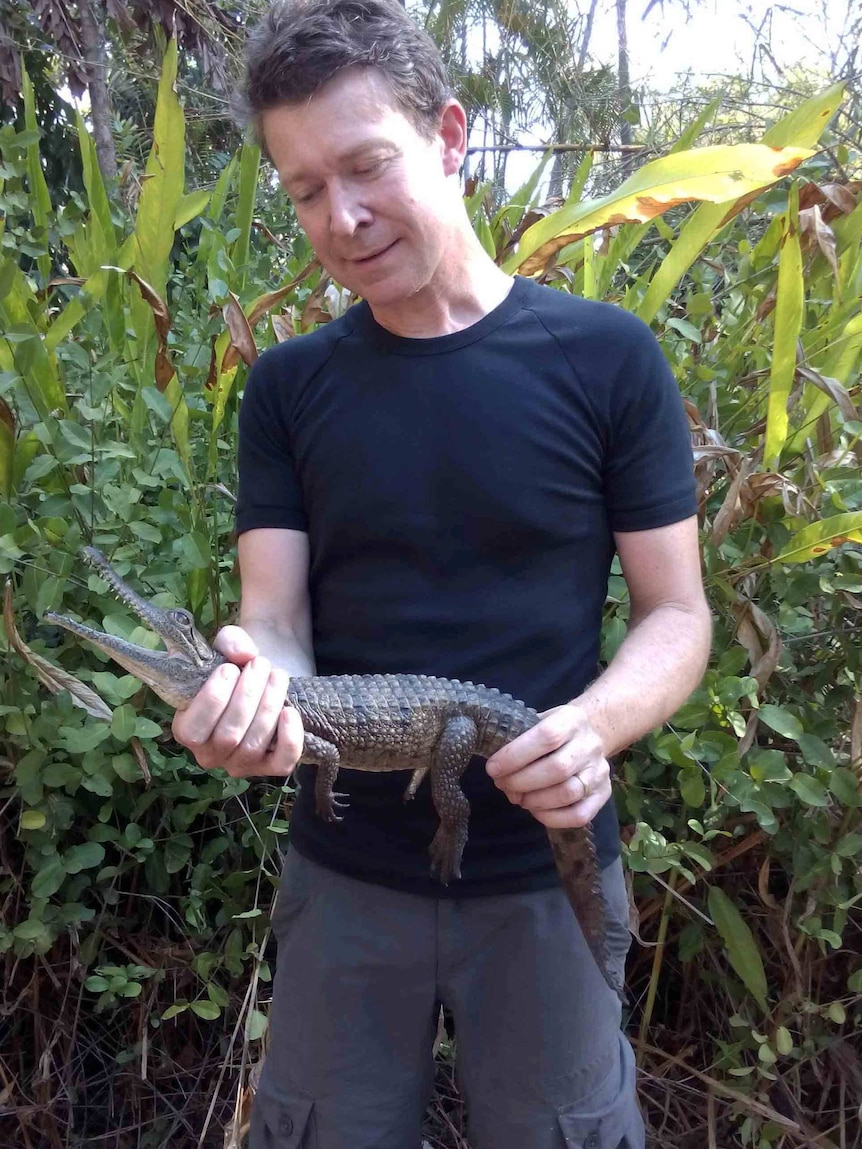 A man holding a very small crocodile.