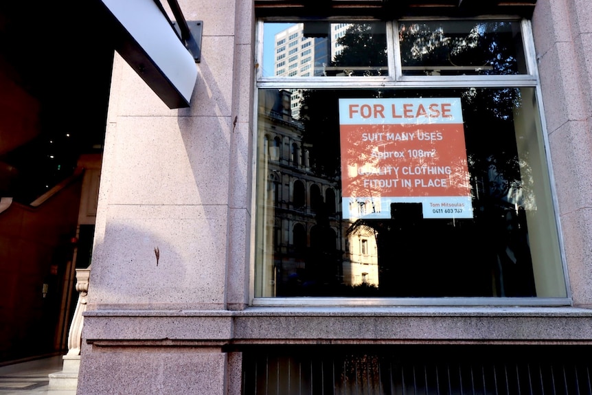 A "For Lease" sign on the window of an empty shop. 