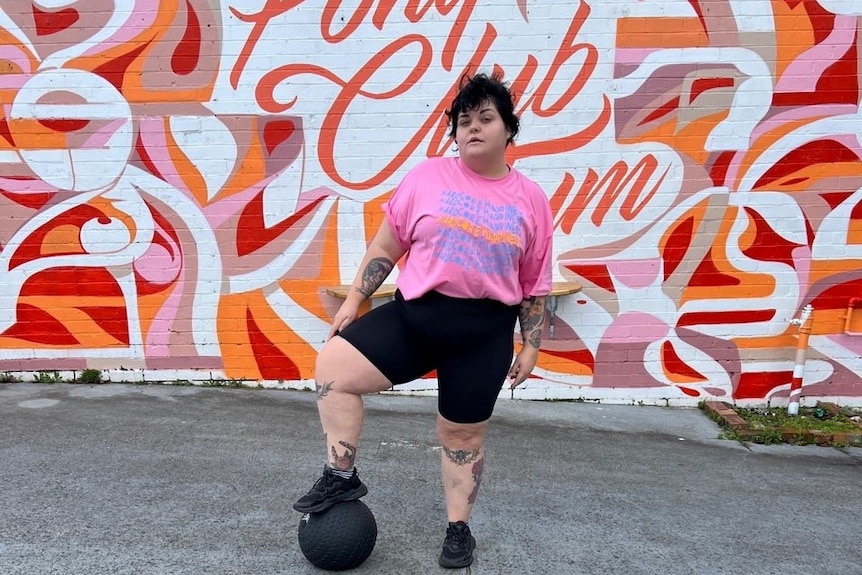 Rose McAlister stands in front of the Pony Club Gym mural in Preston, Melbourne