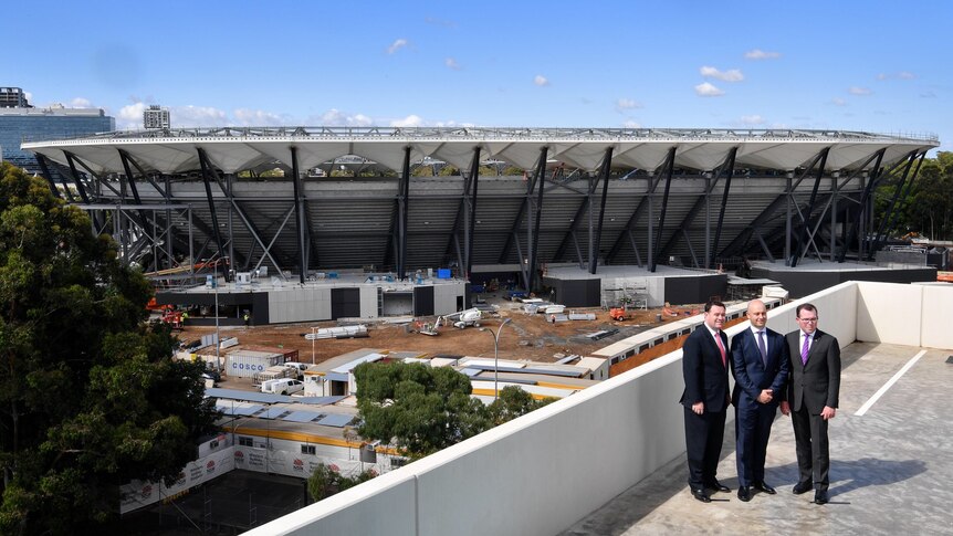 The near-completed Western Sydney stadium, with three men posing for a photo