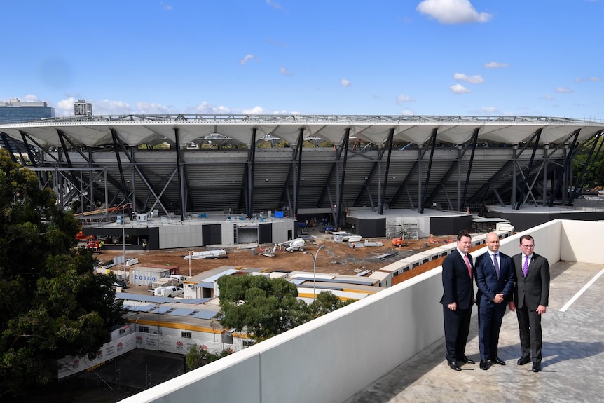 The near-completed Western Sydney stadium, with three men posing for a photo