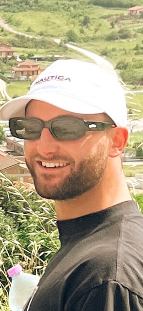 A young man wearing sunglass and a white baseball hat.  