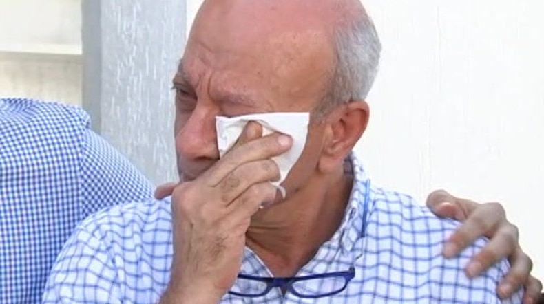 Aiia Maasarwe's father, Saeed, wipes tears from his eyes while another man places a hand on his shoulder.