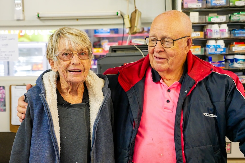 Le couple âgé portant des vestes se tient côte à côte en souriant