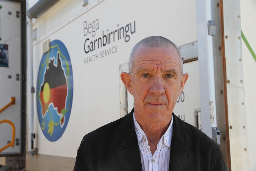 A man, wearing a suit, stands outside a vaccination clinic