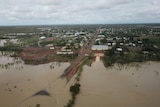 The land surrounding an outback town is under brown water, after flooding.