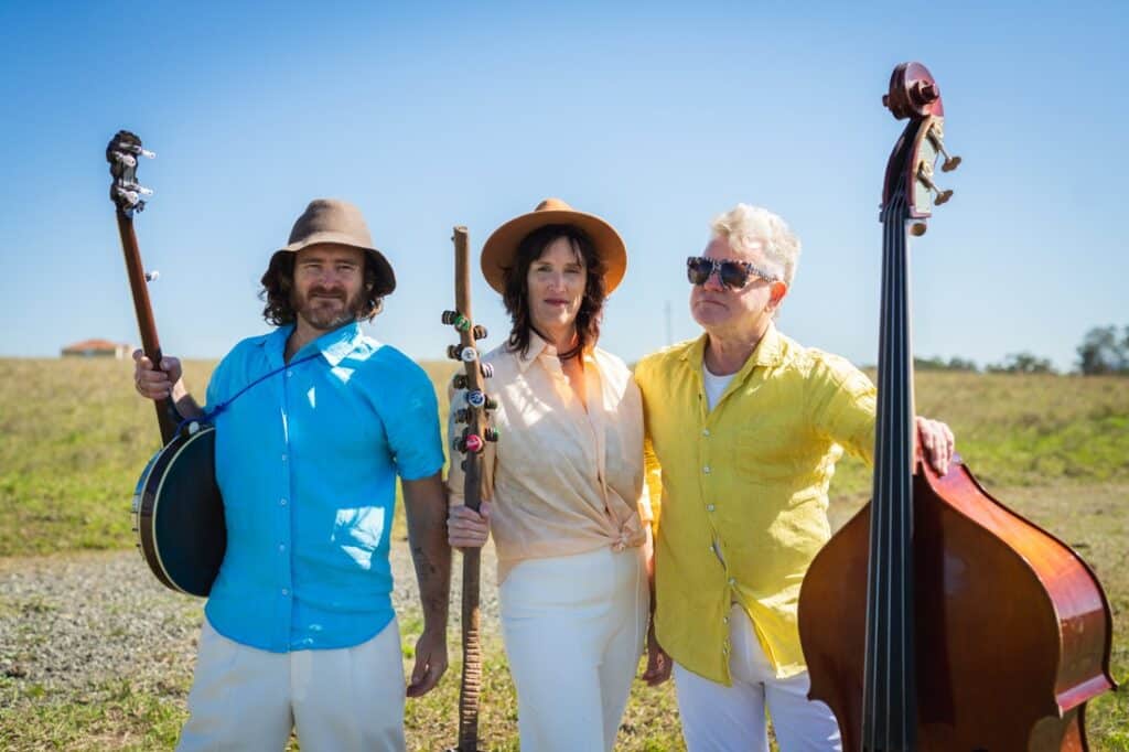 Hunter Valley cosmic country band Magpie Diaries stand against blue sky background in bright shirts.