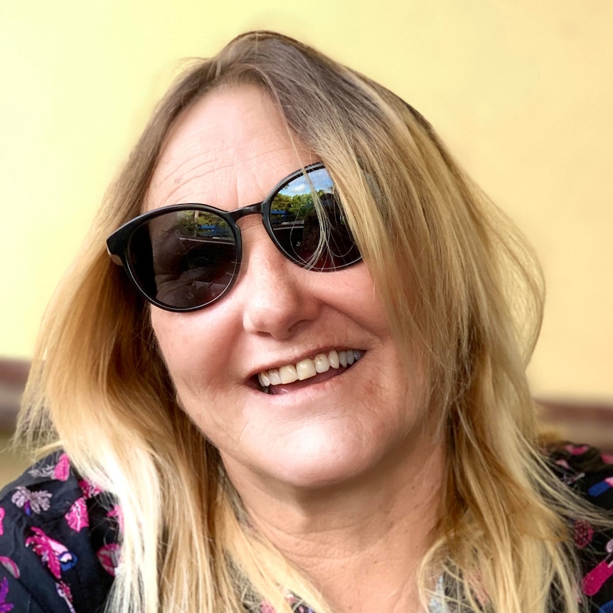 A woman smiling while wearing sunglasses.