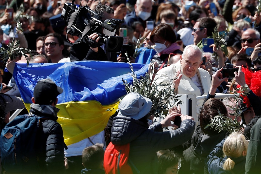 People hold the Ukrainian flag as Pope Francis greets the crowd.