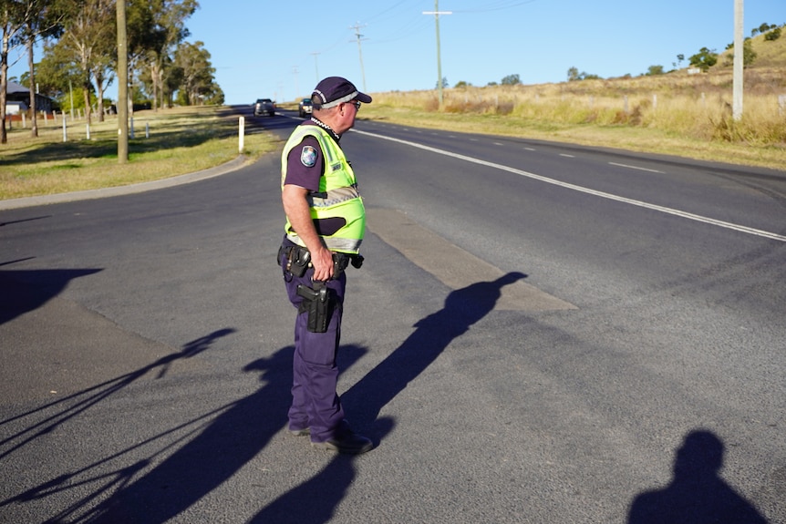 A police officer stands in the middle of a road.